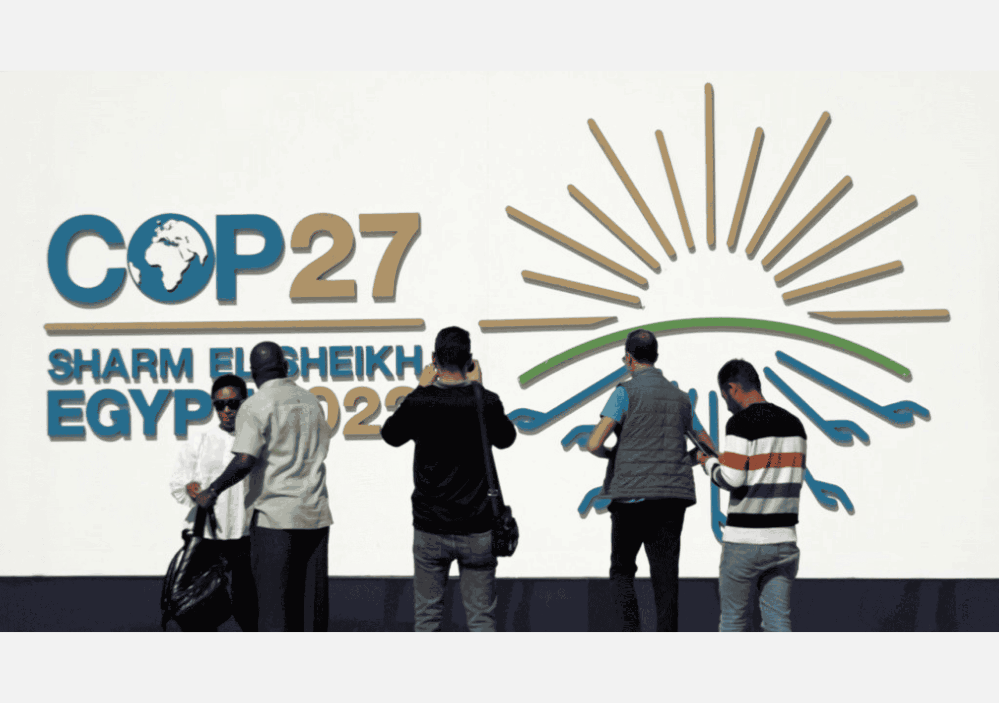 مجموعة من الحاضرين يقفون أمام شعار مؤتمر الأمم المتحدة للمناخ COP27 في مدينة شرم الشيخ المصرية.