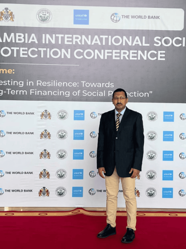 مشاركة عدالة لحقوق الإنسان في مؤتمر الحماية الاجتماعية الدولي محمود جابر أمام لوحة مؤتمر الحماية الاجتماعية الدولي بغامبيا.