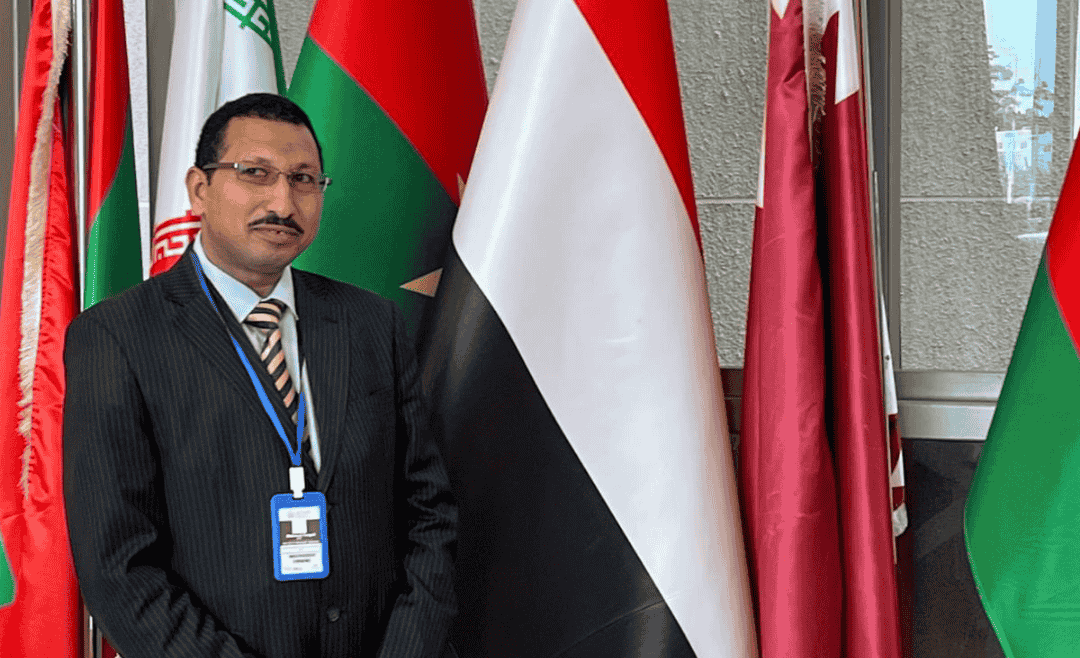 محمود جابر أمام أعلام الدول المشاركة في الدورة الـ85 للجنة الإفريقية لحقوق الإنسان والشعوب.