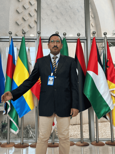 محمود جابر خلال أعمال الدورة الإفريقية لحقوق الإنسان – بانجول محمود جابر أمام أعلام الدول المشاركة في مؤتمر اللجنة الإفريقية لحقوق الإنسان والشعوب.