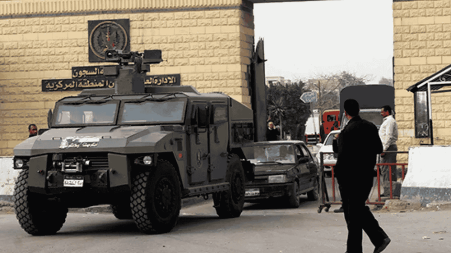 صورة تُظهر مدرعة تابعة لقوات الأمن المصرية تقف أمام بوابة سجن طرة شديد الحراسة بالقاهرة، المعروف باسم “سجن العقرب”، مع تواجد عناصر أمن ومدنيين في محيط البوابة.