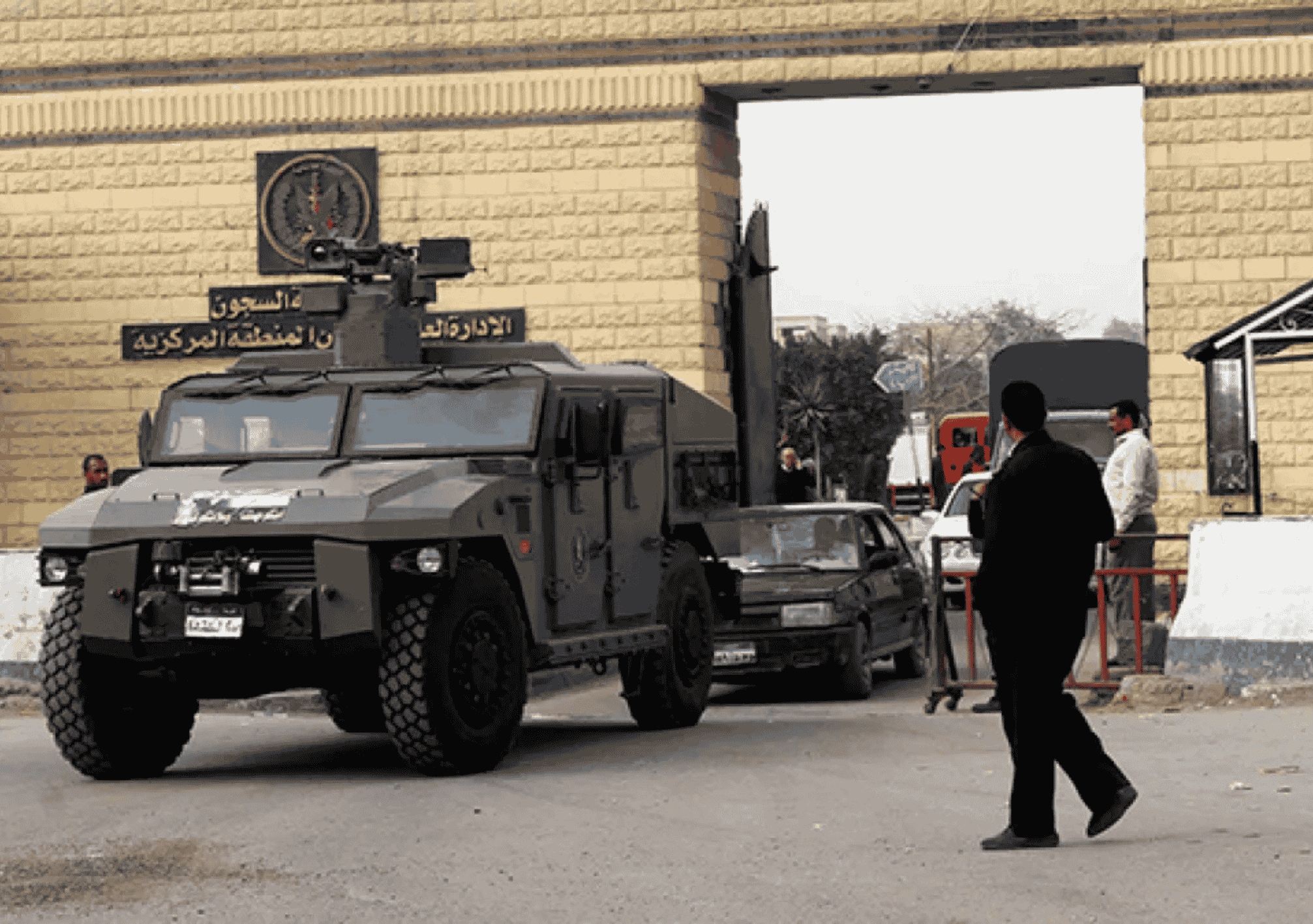 صورة تُظهر مدرعة تابعة لقوات الأمن المصرية تقف أمام بوابة سجن طرة شديد الحراسة بالقاهرة، المعروف باسم “سجن العقرب”، مع تواجد عناصر أمن ومدنيين في محيط البوابة.