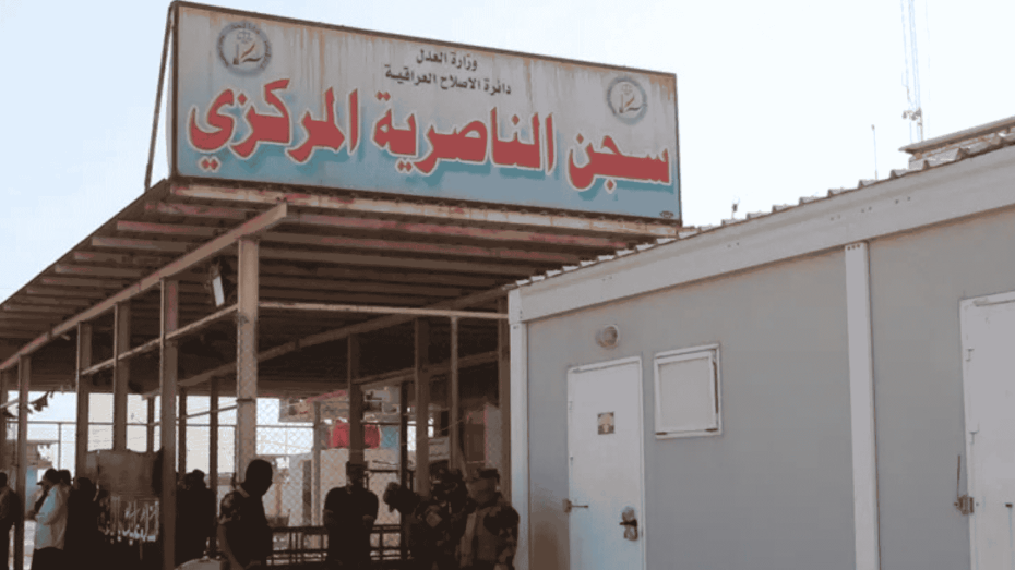 صورة لمدخل سجن الناصرية المركزي في العراق مع وجود قوات أمنية أمام المبنى.