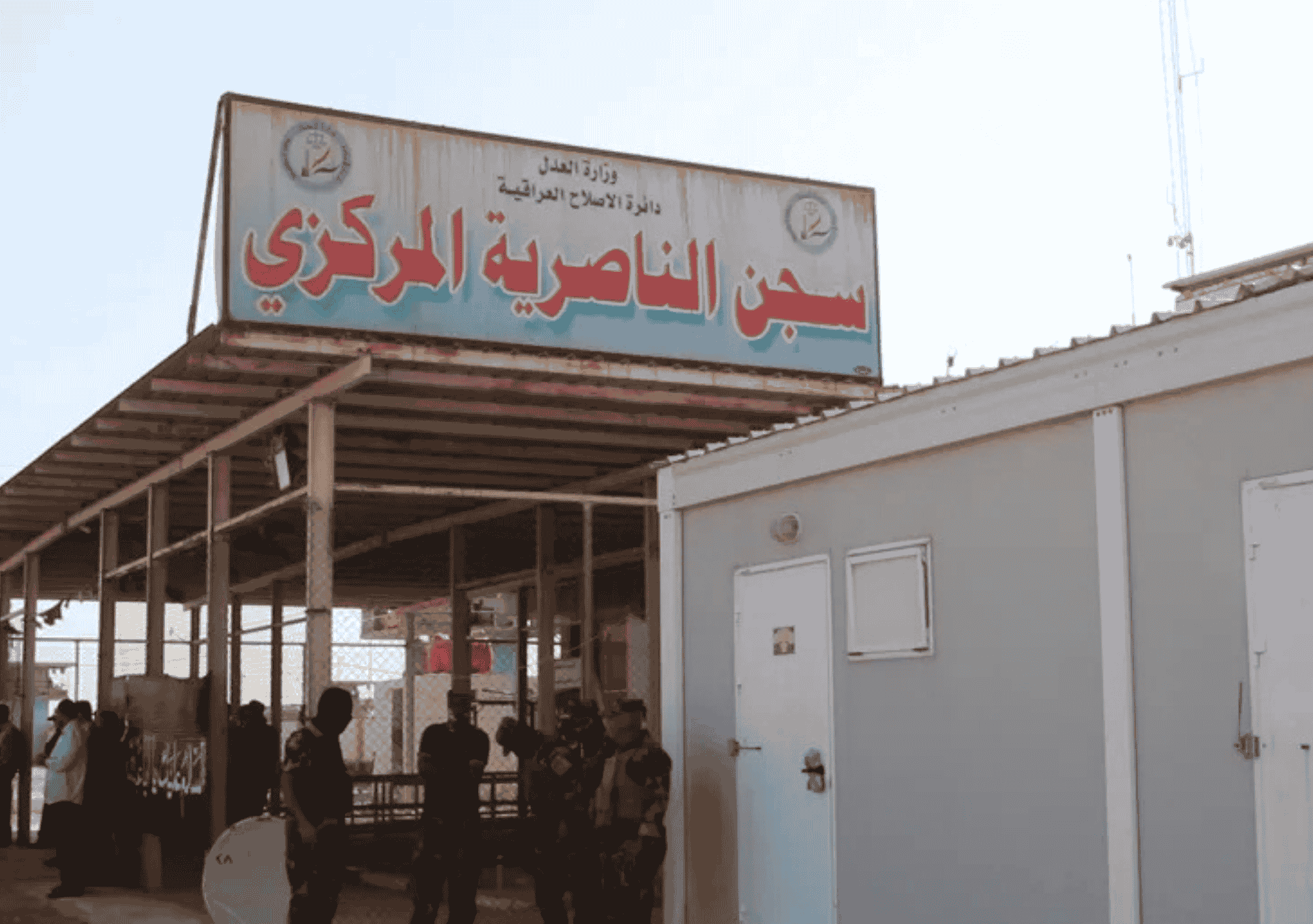 صورة لمدخل سجن الناصرية المركزي في العراق مع وجود قوات أمنية أمام المبنى.