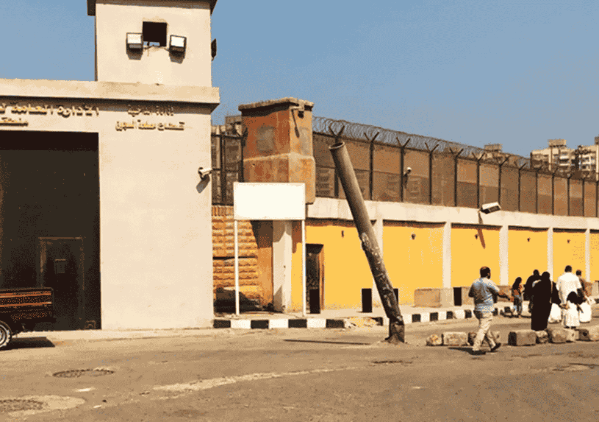 واجهة سجن طرة شديد الحراسة في مصر مع ظهور زوّار يقفون أمام البوابة الرئيسية