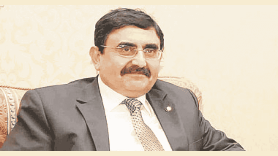 رجل يرتدي بدلة رسمية يجلس على مقعد داخل غرفة ذات طابع رسمي.