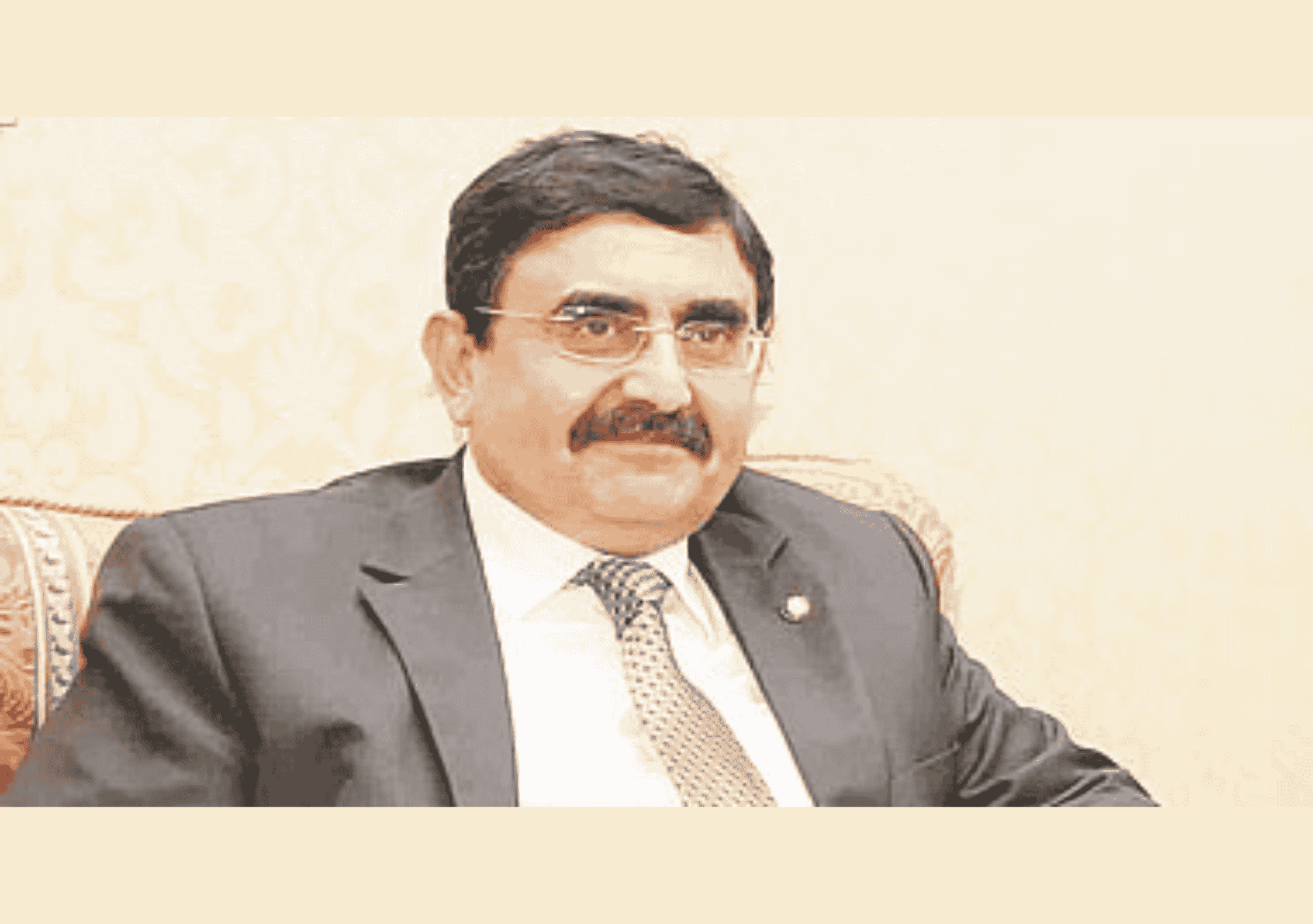 رجل يرتدي بدلة رسمية يجلس على مقعد داخل غرفة ذات طابع رسمي.