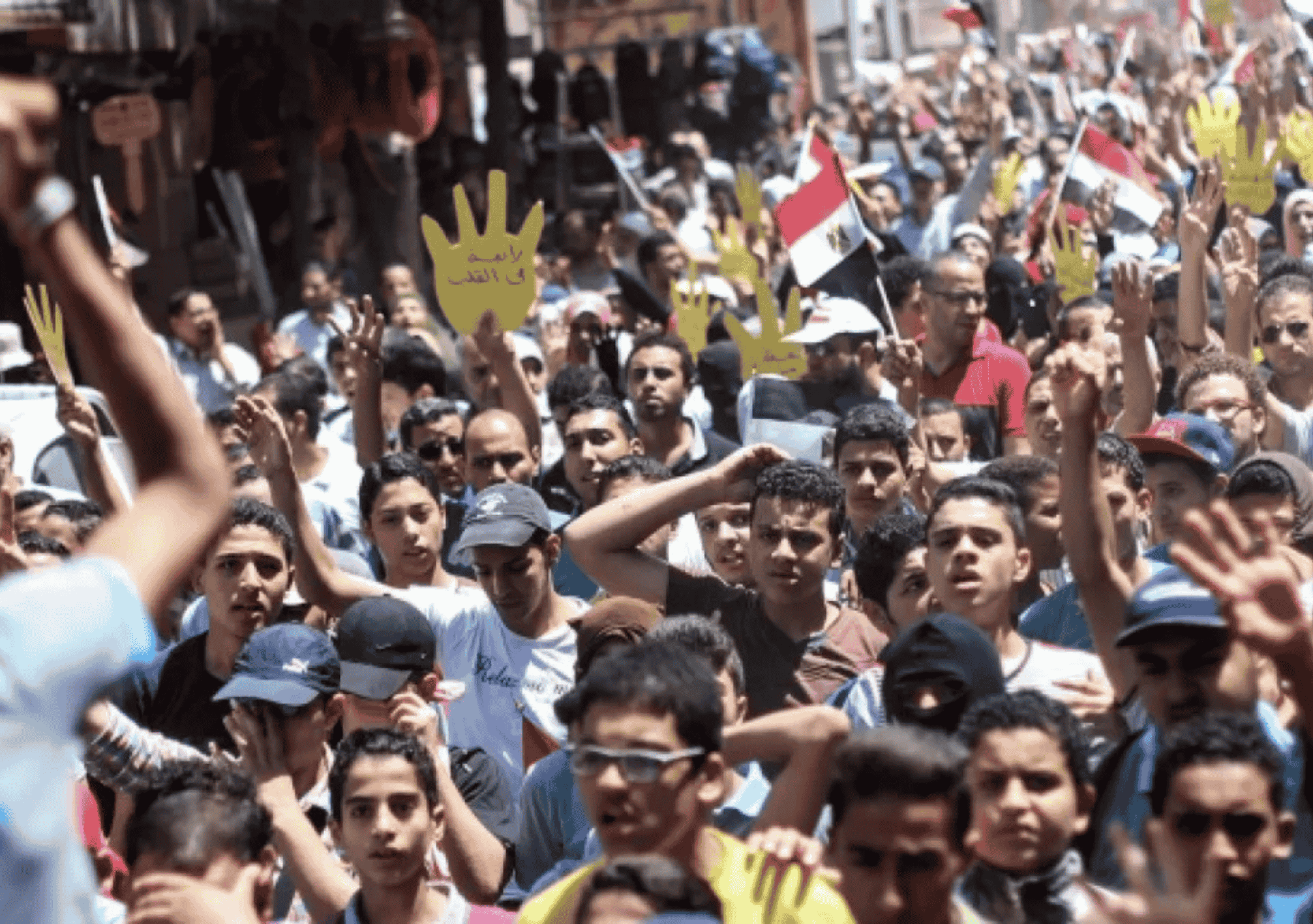 صورة لمتظاهرين في أحد شوارع مصر يرفعون لافتات صفراء وأعلامًا مصرية، تعبيرًا عن احتجاجهم على الانتهاكات الحقوقية والمطالبة بالحرية والعدالة.